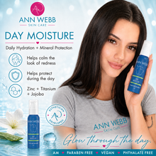 Load image into Gallery viewer, A woman holds a bottle of Ann Webb Skin Care Day Moisture against a bright blue, water-themed background with product benefits and text. The bottle is blue with a white cap, and the image includes the Ann Webb brand logo and product name prominently.
