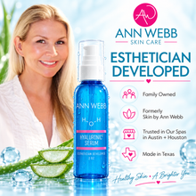 Load image into Gallery viewer, Ann Webb Skin Care Hyaluronic Serum bottle displayed on a bright icy surface with a smiling woman in the background and marketing text on the right.

