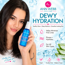 Load image into Gallery viewer, A woman holds a bottle of Ann Webb Skin Care Dewy Hydration Hyaluronic Serum against a bright, icy blue background with water droplets, bubbles, and product benefits listed on the right.
