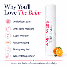 Load image into Gallery viewer, A white cosmetic balm tube labeled 'ANN WEBB THE BALM' stands on a white background beside marketing text listing benefits such as antioxidant care, anti-aging moisture, super hydration, UVA protection, non-greasy feel, and non-irritating comfort. Two orange slices appear near the base of the tube.

