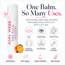 Load image into Gallery viewer, Ann Webb The Balm lip balm stick shown on a white background with promotional text and icons. The white balm tube has red and black lettering and is pictured next to sliced oranges.
