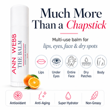 Load image into Gallery viewer, Ann Webb The Balm chapstick-style balm stick shown on a white background with promotional text, icons for lips, under eyes, entire face, dry patches, and body use, plus orange slices at the base.
