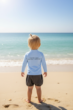 Load image into Gallery viewer, Back view of child at beach wearing rash guard
