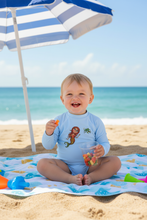 Load image into Gallery viewer, Child relaxing on beach wearing rash guard

